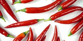 在白色背景上旋转自然成熟的红辣椒，俯视图，4K