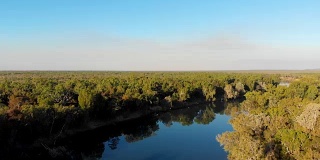 在澳大利亚达尔文茂密的森林中，无人机拍摄到一条弯曲的河流
