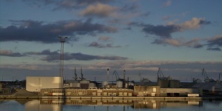 贸易港口日落对蓝色多云的天空。