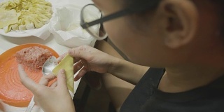 亚洲妇女手工制作馄饨和饺子馅。理念:爱、食物、客人共进晚餐。