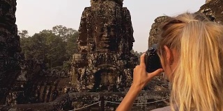 女游客在柬埔寨吴哥窟拍摄古庙和古庙雕刻