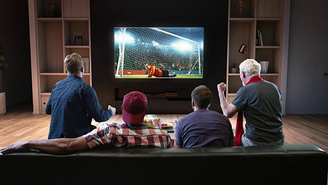 一群球迷正在观看电视上的一个足球时刻，庆祝点球入球