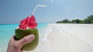 个人观点:马尔代夫阳光明媚的热带海滩上，男人喝着椰子饮料视频素材模板下载