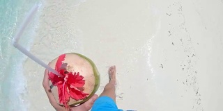 个人视角:马尔代夫，一个男人喝着椰子汁在阳光明媚的海洋中涉水