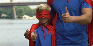 儿童娱乐和男孩超人服装显示大拇指，休闲中心