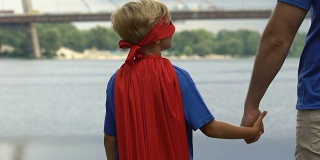 没有安全感的男孩穿着超级英雄服装，找到父亲的支持，手牵手
