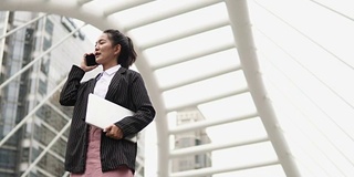 美丽的商业女人在户外使用电话。