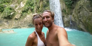 年轻夫妇与美丽的瀑布自拍