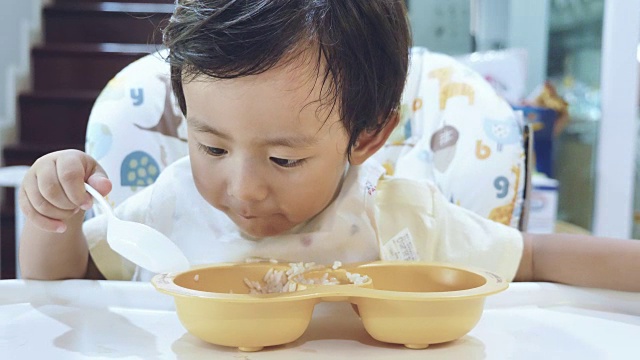 小男孩在高椅子上吃婴儿食品。