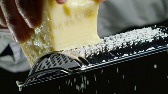 一个厨师磨碎的帕玛森奶酪，典型的意大利奶酪，在盘子里刚刚酿造。