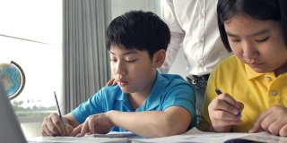 辅导学生在课堂上使用笔记本电脑学习。4K慢镜头亚洲儿童在家与老师学习。