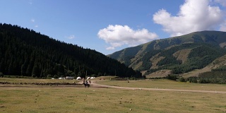 骑马者在田野与天山山脉在吉尔吉斯斯坦