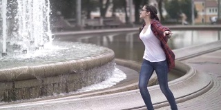 快乐女孩在城市公园附近的喷泉嬉戏，蹦蹦跳跳跑着幸福生活