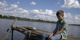 被冒犯的男孩坐在湖边的码头上，想着一些事情，压力，抑郁