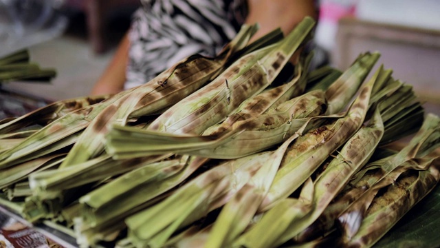 Sweet sticky rice with banana pastry covered by banana leaf grilled on barbecue.
