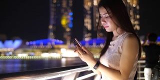 亚洲女孩旅行者在晚上使用手机