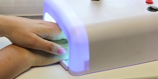 一个女人在做美甲。用紫外线灯烘干清漆。