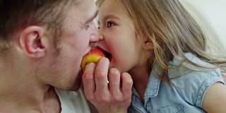 可爱的女孩和咬苹果的爸爸