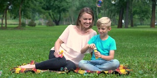 快乐的男孩吹泡泡，妈妈和儿子在公园玩，快乐的共同度假