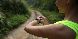 一名亚洲女子在登山前设置了运动手表。慢动作