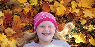 一个美丽的女孩的肖像在秋天公园的落叶上