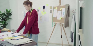 年轻的亚洲女性时装设计师在工作室工作时，用铅笔和看纸画画。