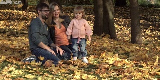 快乐的一家人在秋天的公园里玩枫叶