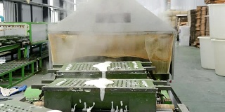 在橡胶枕厂，金属橡胶枕模具在传送带上用蒸汽加热出模