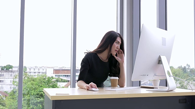 女商人在工作场所使用电脑。年轻的亚洲女商人思考和工作在电脑办公室