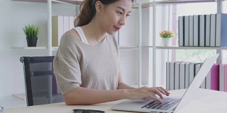 有吸引力的年轻亚洲女人在家里工作看着笔记本电脑兴奋，惊喜或感觉震惊的自由职业者潮概念的好消息。