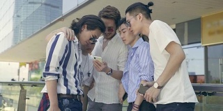 年轻的亚洲成年男子在街上闲逛，看手机