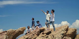 年轻的亚洲成年男子站在海边的岩石上