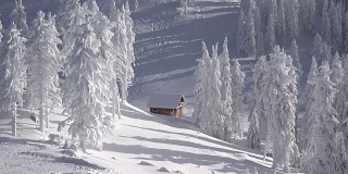 壮丽的冬季景观，群山和覆盖着积雪的冷杉树，孤立的小木屋，斜坡上的滑雪者，光影的流逝