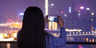 年轻女子在城市的夜晚拍照