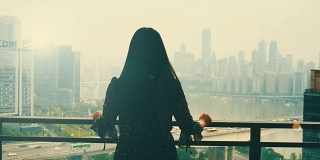 年轻的女人，站在阳台上，看着城市
