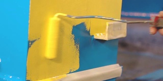 男子正在用手把蓝色的金属细节涂成黄色
