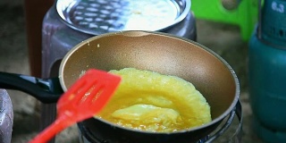女人正在平底锅里煎蛋卷。