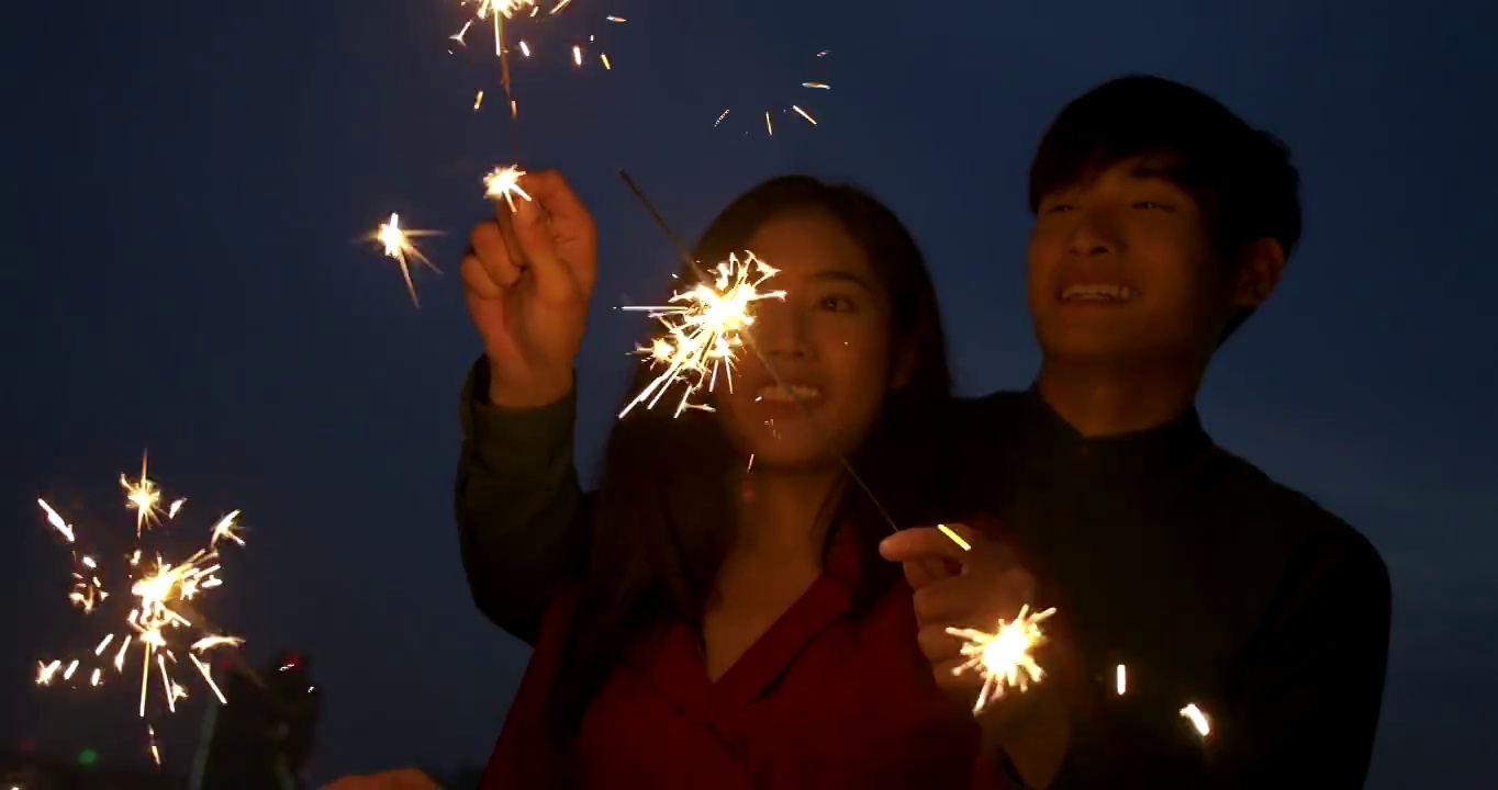 年轻的亚洲夫妇一起在屋顶玩烟花慢镜头。