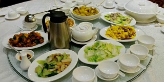 圆形玻璃桌子旋转中国食物，肉类和茶与家人在餐厅