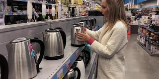 一名年轻女子在一家家居用品商店挑选一个水壶