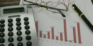 办公桌上有商业图表，眼镜，钢笔和计算器。滑块。商业和金融,