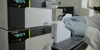这是一位研究人员在大学基因实验室检查高效液相色谱(HPLC)的手持镜头