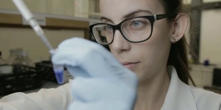 这是一名研究人员在大学基因实验室中移液样本的手持镜头