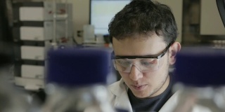 这是大学基因实验室里研究人员将样本移到erlenmeyerl的手持镜头