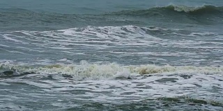 海浪拍打着沙滩，溅起水花，慢镜头