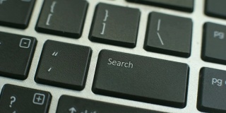 电脑键盘上的搜索按钮，女性的手指按下按键