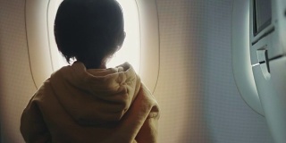 幼童正在通过窗户看全景飞机