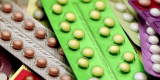 口服避孕药在药房柜台与彩色药丸条的背景。