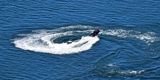 男人骑着摩托艇越过蓝色的海水