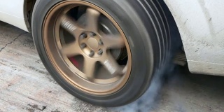 拖曳车让轮胎冒着烟热身，赛车烧坏了轮胎上的橡胶，为比赛做准备。